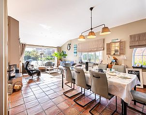 Gezellige woonkamer van vakantiehuis Le Palmier in Koksijde, West-Vlaanderen, met eethoek en uitzicht op de tuin.