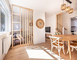 Lichte en moderne woonkamer van vakantiehuis Ensemble in Koksijde, West-Vlaanderen, met houten accenten en comfortabele zithoek.