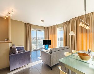 Lichte woonkamer in Vue Dunes vakantiehuis, Koksijde, met moderne inrichting en panoramisch uitzicht op de duinen van West-Vlaanderen.