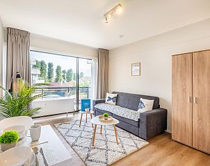 Helles Wohnzimmer des Ferienhauses En Amoureux in Koksijde, Westflandern, mit komfortabler Einrichtung und Blick auf die grne Umgebung.