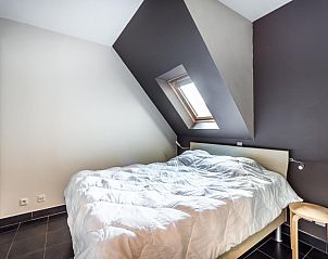 Sfeervolle slaapkamer in Le Penthouse, een vakantiehuis in Koksijde, West-Vlaanderen, met een dakraam voor natuurlijk licht.