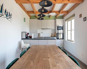 Moderne Kche des Ferienhauses Westhinder I H4 in Koksijde, Westflandern, mit Holzbalken und groem Esstisch fr einen gemtlichen Aufenthalt.