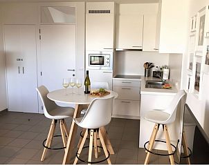 Entspannen Sie sich auf der sonnigen Terrasse des Ferienhauses Westhinder I H36 in Koksijde, Westflandern, mit Blick auf einen grnen Garten.