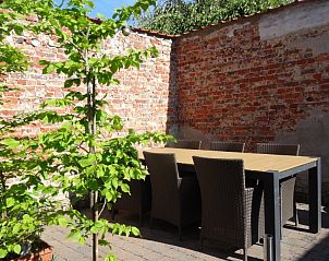 Sunny terrace of maison Miest vacation home in Watou, West Flanders with outdoor furniture surrounded by brick walls.