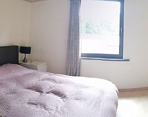 Comfortable bedroom of maison Miest in Watou, West Flanders with large window and natural light.