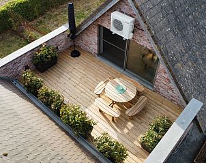 Gemtliche Terrasse des Ferienhauses in Poperinge, Westflandern, mit Holzmbeln und Grnpflanzen, ideal zum Entspannen.