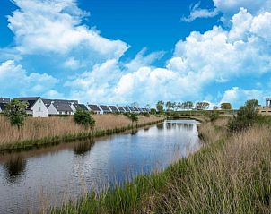 Rustig uitzicht op de natuur rondom vakantiehuis Nieuwendamme 108 in Lombardsijde, West-Vlaanderen, met een serene waterpartij.