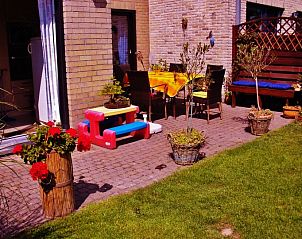 Veranda of vacation home Katica in Bredene, West Flanders with colorful sitting area and green garden