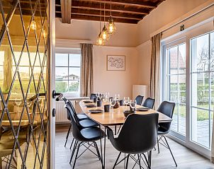 Gezellige eetkamer in vakantiehuis LaCte in Sint-Idesbald, West-Vlaanderen, met houten plafond en uitzicht op de tuin.