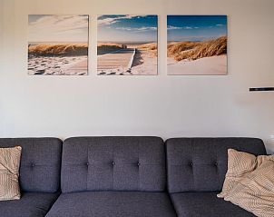 Gezellige woonkamer van vakantiehuis LaCte in Sint-Idesbald, Belgi, met kunstwerken van de kust op de muur.