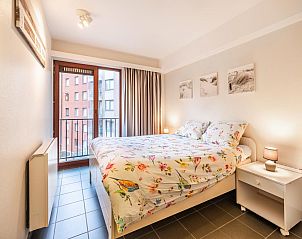 Attraktives Schlafzimmer in Anais drittem Ferienhaus in Sint-Idesbald, Westflandern, mit geblmter Bettwsche und Stadtblick.