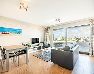 Moderne woonkamer in La Digue vakantiehuis, Sint-Idesbald, Belgi, met uitzicht op terras en natuurlijke omgeving.