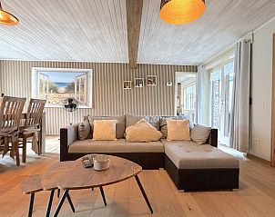 Gemtliches Wohnzimmer des Ferienhauses Bella Casa in Ramskapelle, Westflandern, mit bequemer Sitzecke und Holzinterieur.