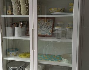 Vrolijk ingerichte kast met servies in Vakantiehuis Alegria, Westende, West-Vlaanderen.