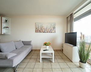 Modern living room in Apartment Residentie Astrid in Bredene, West Flanders, Belgium, with comfortable sitting area and large window with a view.