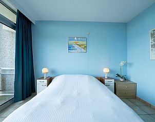Bedroom in Apartment Residentie Astrid, Bredene, West Flanders, with blue interior and view of balcony.