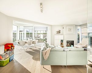 Lichte woonkamer van vakantiehuis La Perle in Oostduinkerke, West-Vlaanderen met moderne inrichting en uitzicht op het terras.