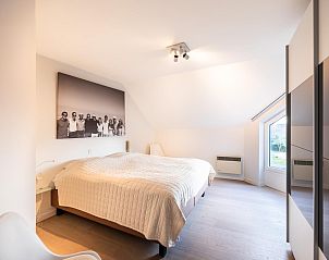 Sfeervolle slaapkamer in La Perle vakantiehuis, Oostduinkerke, Belgi met comfortabel bed en groot raam voor veel natuurlijk licht.