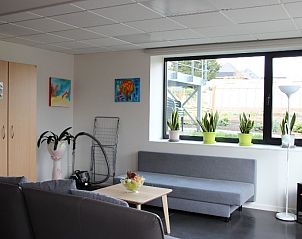 Lichte woonkamer in DE KLEPPE vakantiehuis Brakel, met comfortabele zitruimte en uitzicht op de tuin.
