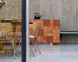 Stijlvolle eetkamer in Vakantiehuis in Sint-Pauwels, Oost-Vlaanderen, met houten meubels en betonnen muren.
