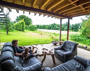 Overdekt terras van Aan de Jordaan vakantiehuis in Willebringen, Vlaams-Brabant met comfortabel meubilair en uitzicht op groene velden.