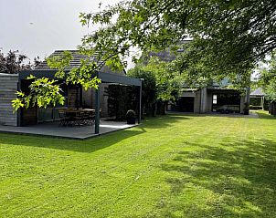 Groene tuin met terras bij vakantiehuis Wilgentuin in Bekkevoort, Vlaams-Brabant, ideaal voor ontspanning.