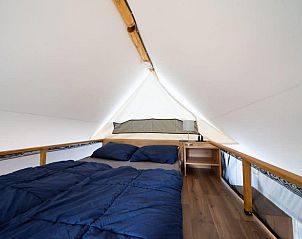 Sfeervolle slaapkamer in Kiezel Lodge XL, een glamping lodge in Mol, Antwerpen, Belgi, met comfortabel bed en houten interieur.