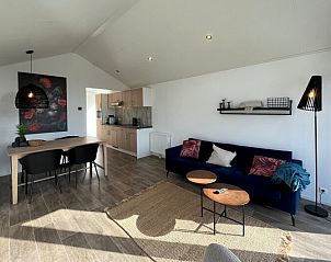 Gezellige woonkamer in Chalet in Mol, Antwerpen, met moderne inrichting en open keuken, ideaal vakantiehuis voor ontspanning.