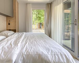 Lichte slaapkamer in Chalet in Mol, Antwerpen, met uitzicht op de groene natuur en toegang tot een ruim terras.