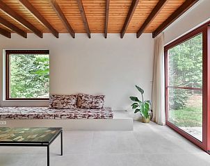 Gezellige woonkamer in Vakantiehuisje in Geel, Winkelomheide, met uitzicht op de natuur door grote ramen en een comfortabele zithoek.