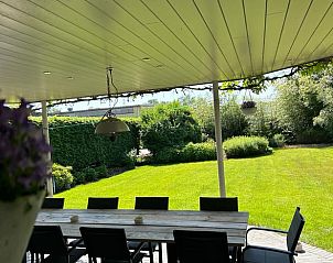 Overdekt terras van Vakantiehuisje in Malle met uitzicht op een weelderige tuin, perfect voor buitenactiviteiten in Antwerpen.