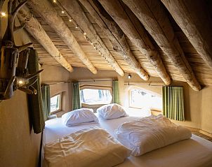 Gemtliches Schlafzimmer im Hobbit House, einem Ferienhaus in Maaseik, Limburg, Belgien, mit Holzbalken und Tageslicht.