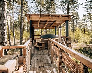 Erhhte Holzveranda mit Whirlpool im Treetop-Ferienhaus in Maaseik, Limburg, Belgien, umgeben von ruhiger Natur.