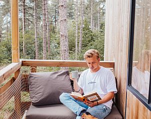Genieen Sie die Entspannung auf der Veranda des Ferienhauses Treetop + Hot Tub in Maaseik, Limburg, Belgien, umgeben von ruhiger Natur.