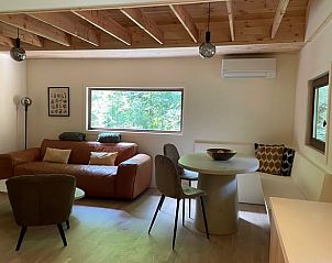 Gemtliches Wohnzimmer von Huisje in Lanaken, einem Ferienhaus in Limburg, Belgien, mit moderner Einrichtung und Blick auf die grne Umgebung.