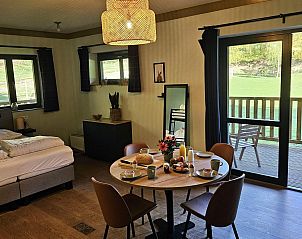 Das Comfort Studio (4p) in Neeroeteren, Limburg, Belgien, bietet einen gemtlichen Innenbereich mit einem Essbereich und Blick auf die grne Umgebung von der Terrasse aus.