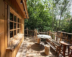 Gezellig terras van Tree House 2 in Neeroeteren, Limburg, Belgi, met houten zitplaatsen en uitzicht op de omringende natuur.