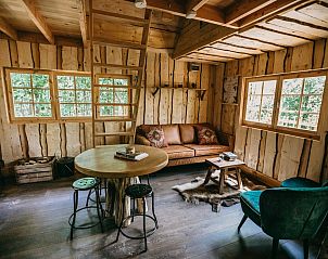 Sfeervolle binnenruimte van Tree House 2 in Neeroeteren, Limburg, Belgi, met houten interieur en comfortabele zithoek.