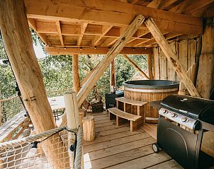 Interieur des Baumhauses 1 in Neeroeteren, Limburg, Belgien, mit Holzinterieur und gemtlicher Sitzecke.
