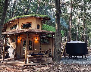 Hobbit House 2 in Neeroeteren, Belgi, vakantiehuis met groene dakbedekking en houten veranda omringd door bomen.