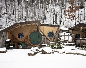 Hobbit House 1 in Neeroeteren, Limburg, Belgien, ein einzigartiges Ferienhaus mit einer rustikalen Veranda, umgeben von ppiger Natur.