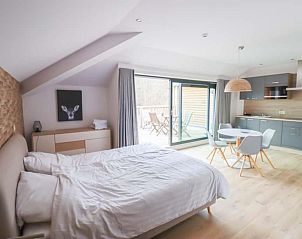 Lichte slaapkamer en keuken in Plus Studio, een vakantieverblijf in Neeroeteren, Limburg, met toegang tot een balkon.