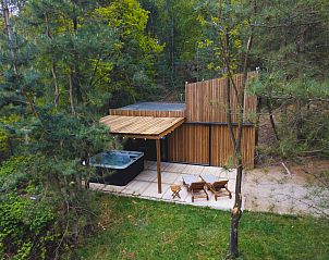 Comfort Sweet Wellness vakantiehuis in Neeroeteren, Limburg met houten terras en jacuzzi omringd door natuur.