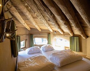 Gezellige slaapkamer in Huisje in Maaseik, vakantiehuis in Neeroeteren, Limburg, Belgi, met rustieke houten balken en sfeervolle verlichting.