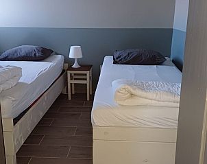 Slaapkamer met tweepersoonsbed en warme inrichting in Aan Maas & Grens vakantiehuis in Kinrooi, Limburg, Belgi.