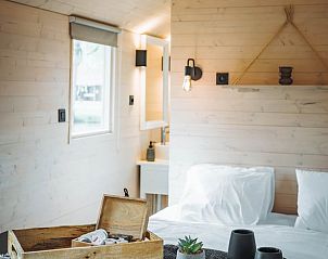 Gezellige binnenruimte van Vakantiehuisje in Kinrooi met comfortabel bed en rustieke houten afwerking.