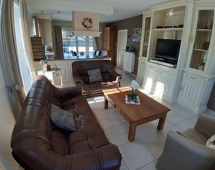 Gezellige woonkamer in De Maaskei vakantiehuis, Kinrooi, Limburg met comfortabele leren banken en een rustieke inrichting.