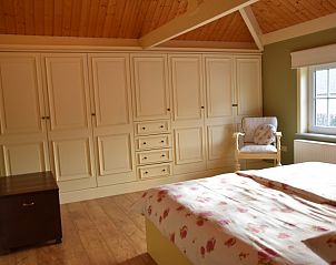 Sfeervolle slaapkamer in De Maaskei vakantiehuis, Kinrooi, Limburg met houten plafonds en een grote kledingkast.