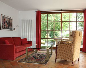 Cozy living room in Holiday Home am Teich, Hombourg, Ardennes overlooking the garden through large windows and comfortable seating.