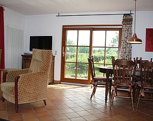 Cozy living room in Holiday Home am Teich, Hombourg, Ardennes overlooking the garden through large windows.